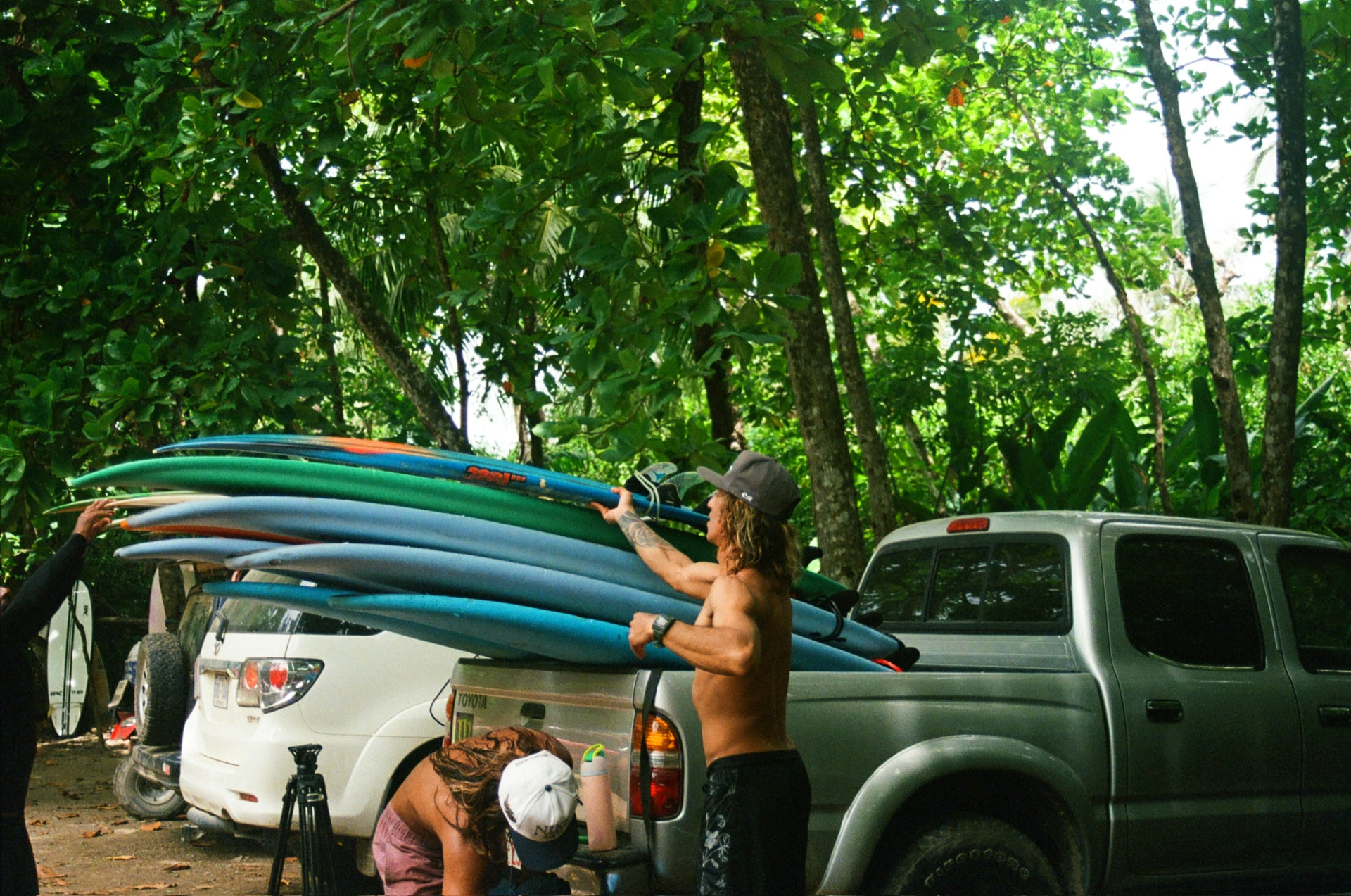 Loading surfboards onto the truck under the trees before a session in Santa Teresa