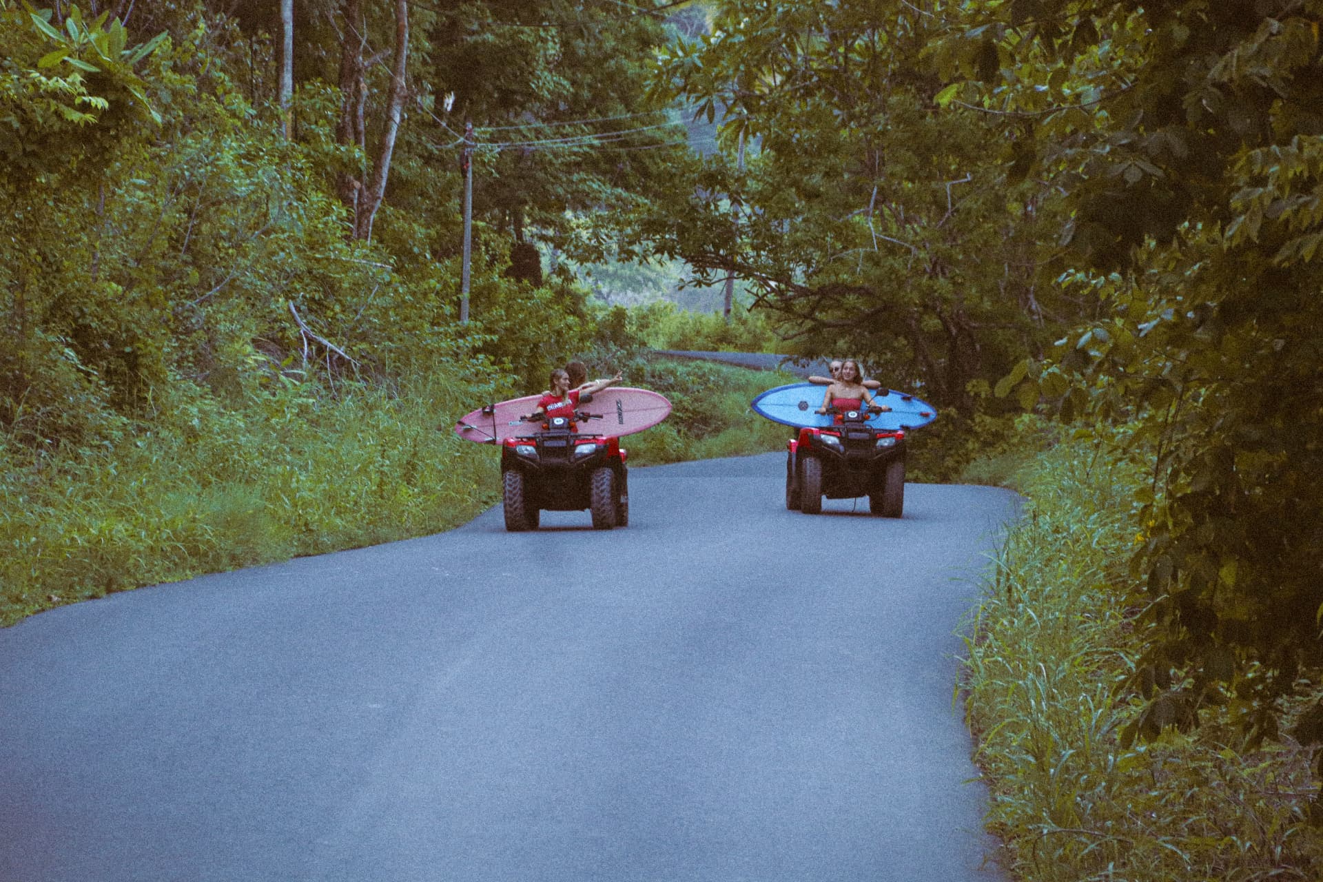 Two ATVs carrying surfboards down a jungle road near Montezuma on a Beach Boys day trip