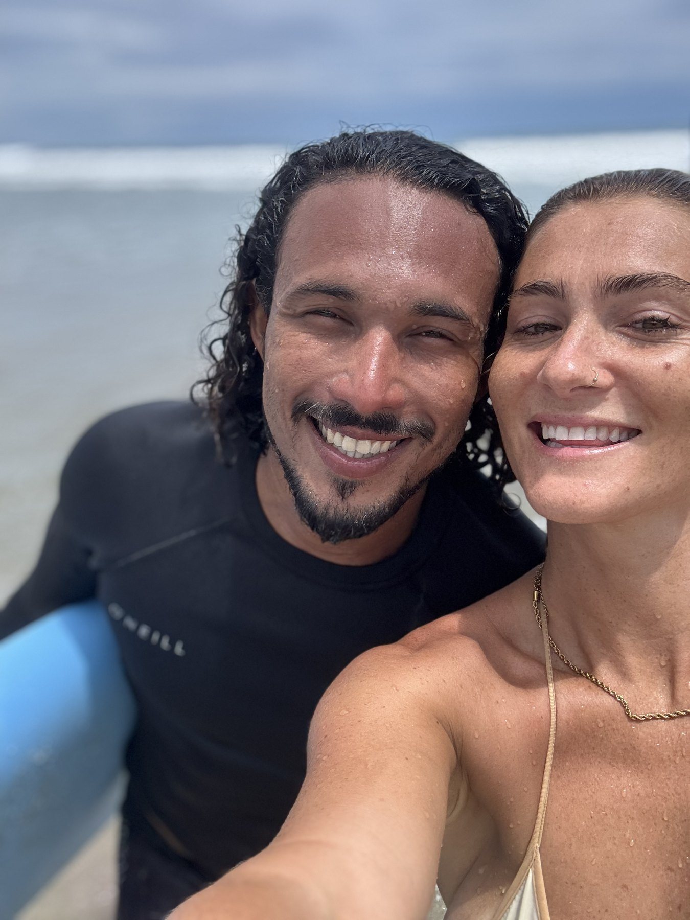 Isaac and a guest smiling in the shallows after a surf lesson in Santa Teresa