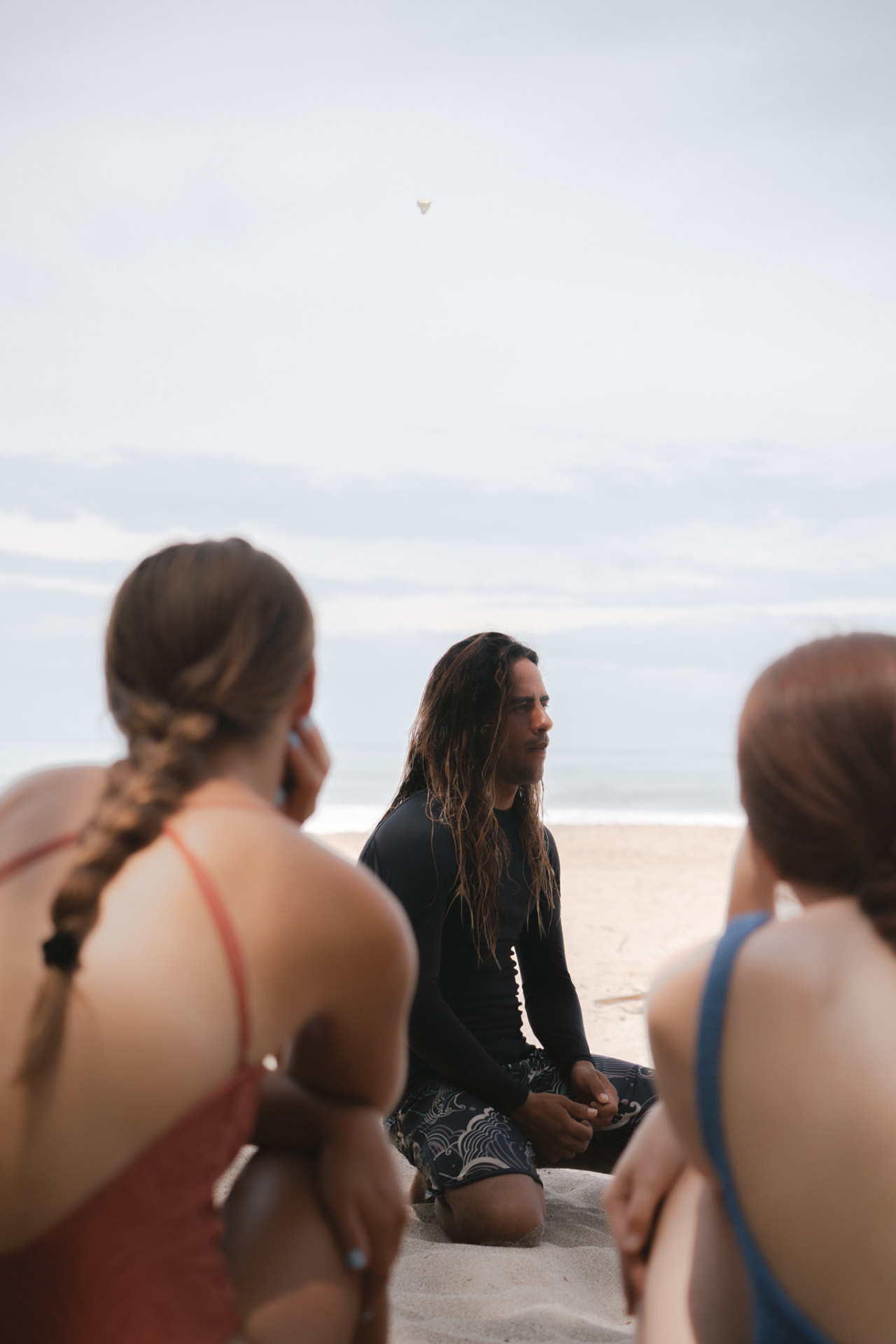 A surf coach talking through footage with guests on the beach