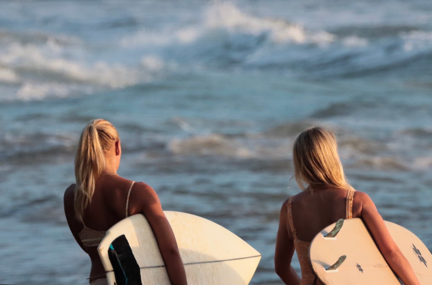 Two surfers walking side by side toward the golden Santa Teresa shorebreak