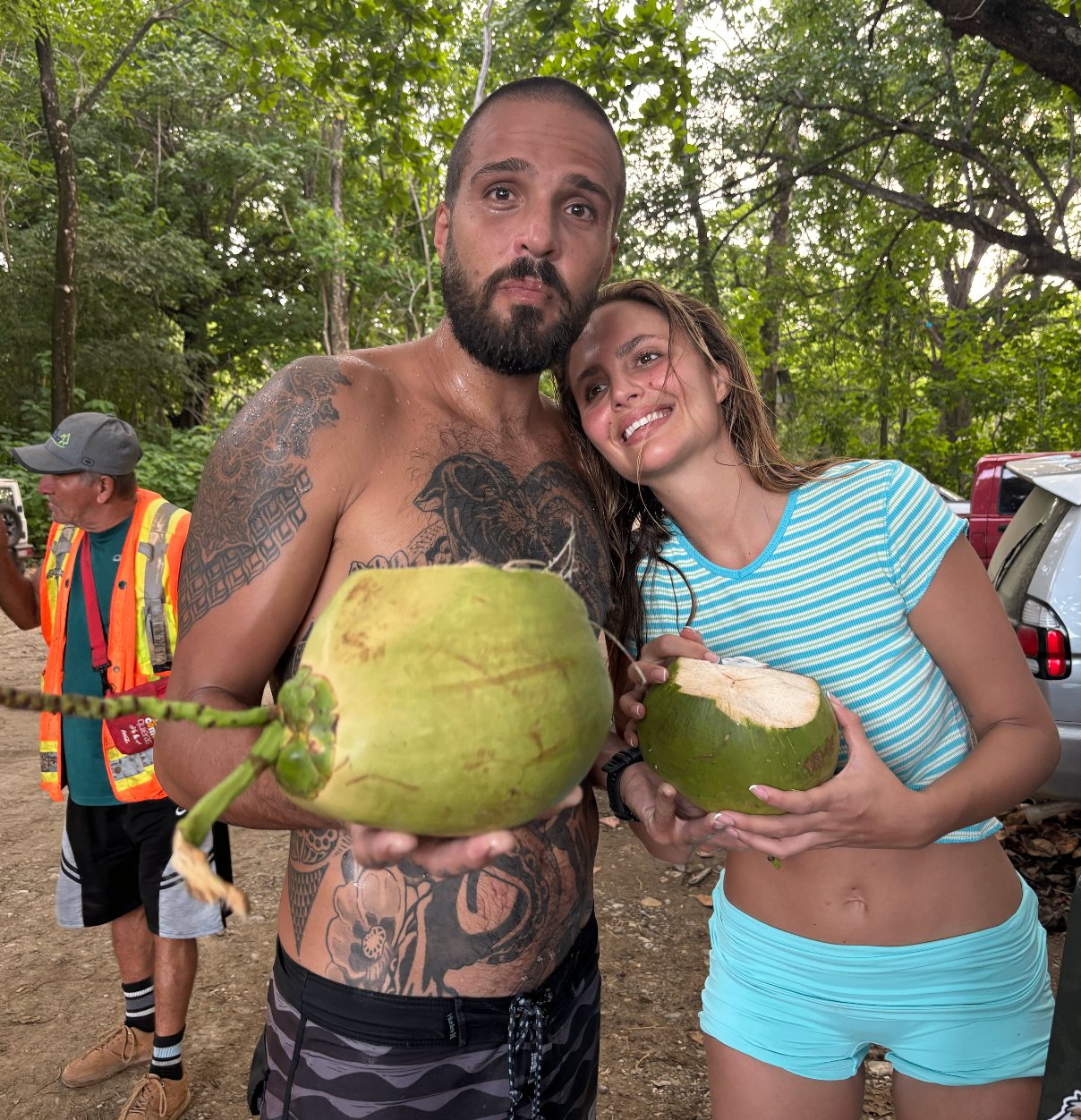 Two of the crew holding fresh coconuts at a roadside stop near Santa Teresa