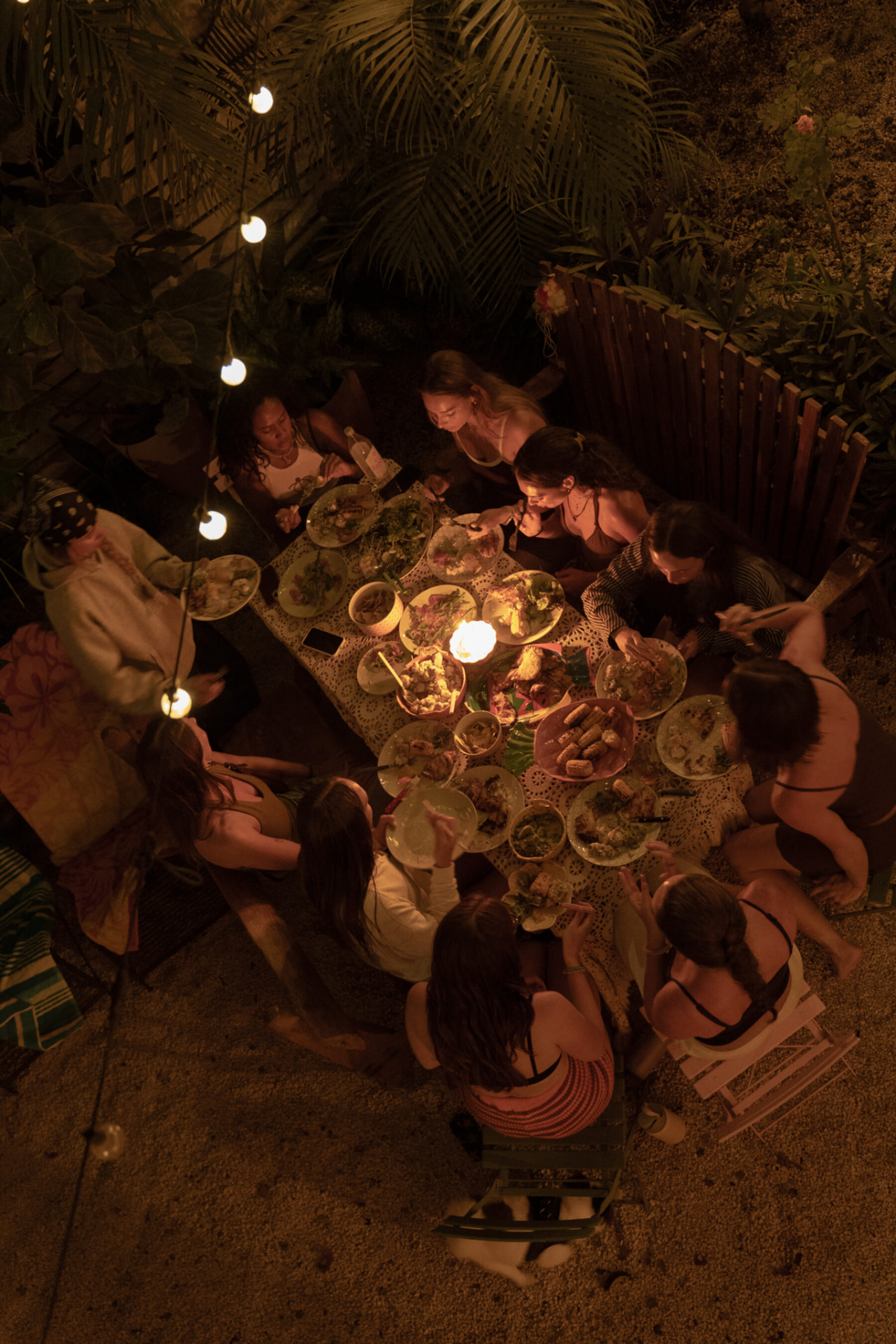 Overhead view of a long candlelit table of Costa Rican food shared under the palms