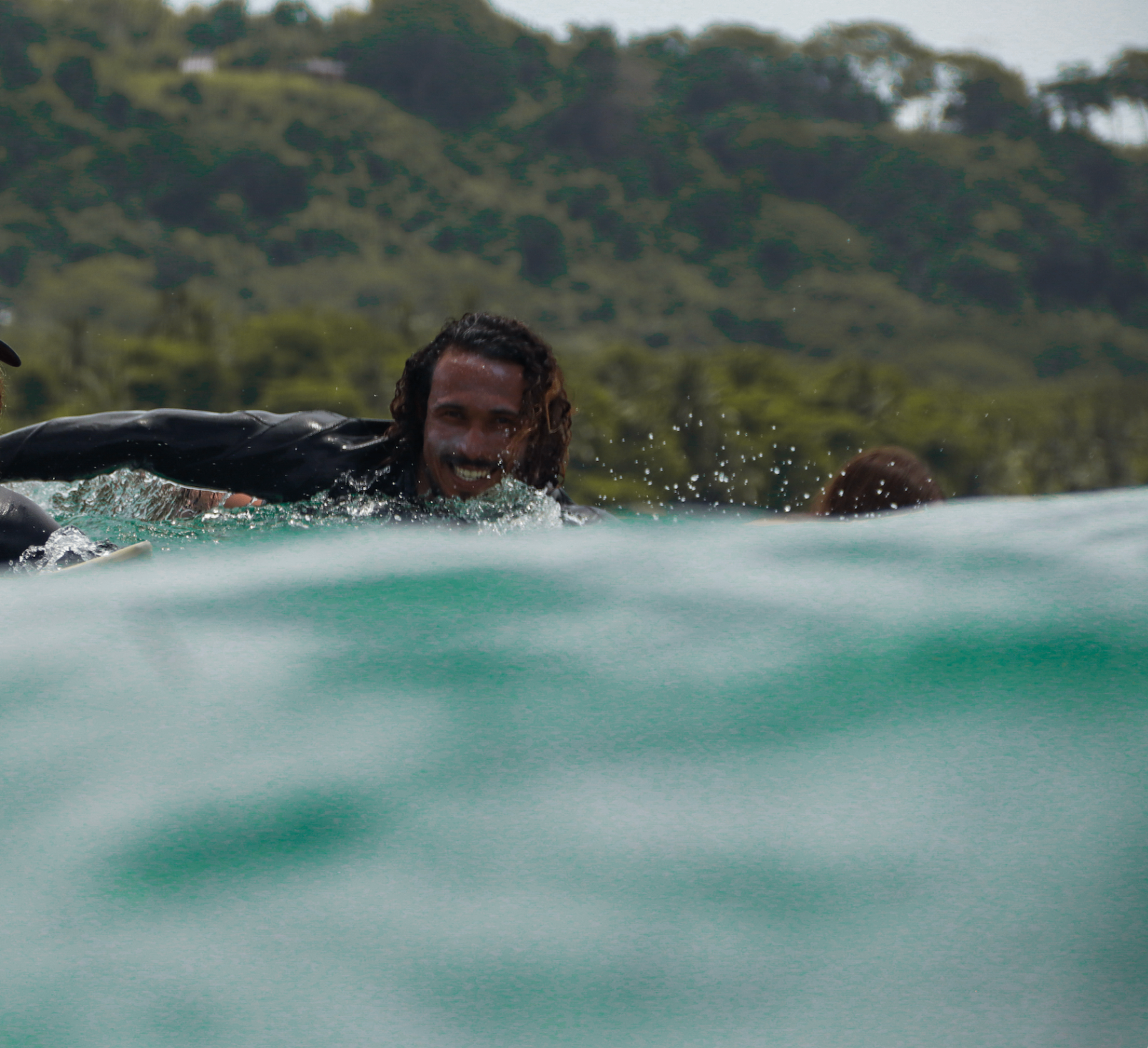 Isaac smiling as he paddles through the line-up in Santa Teresa