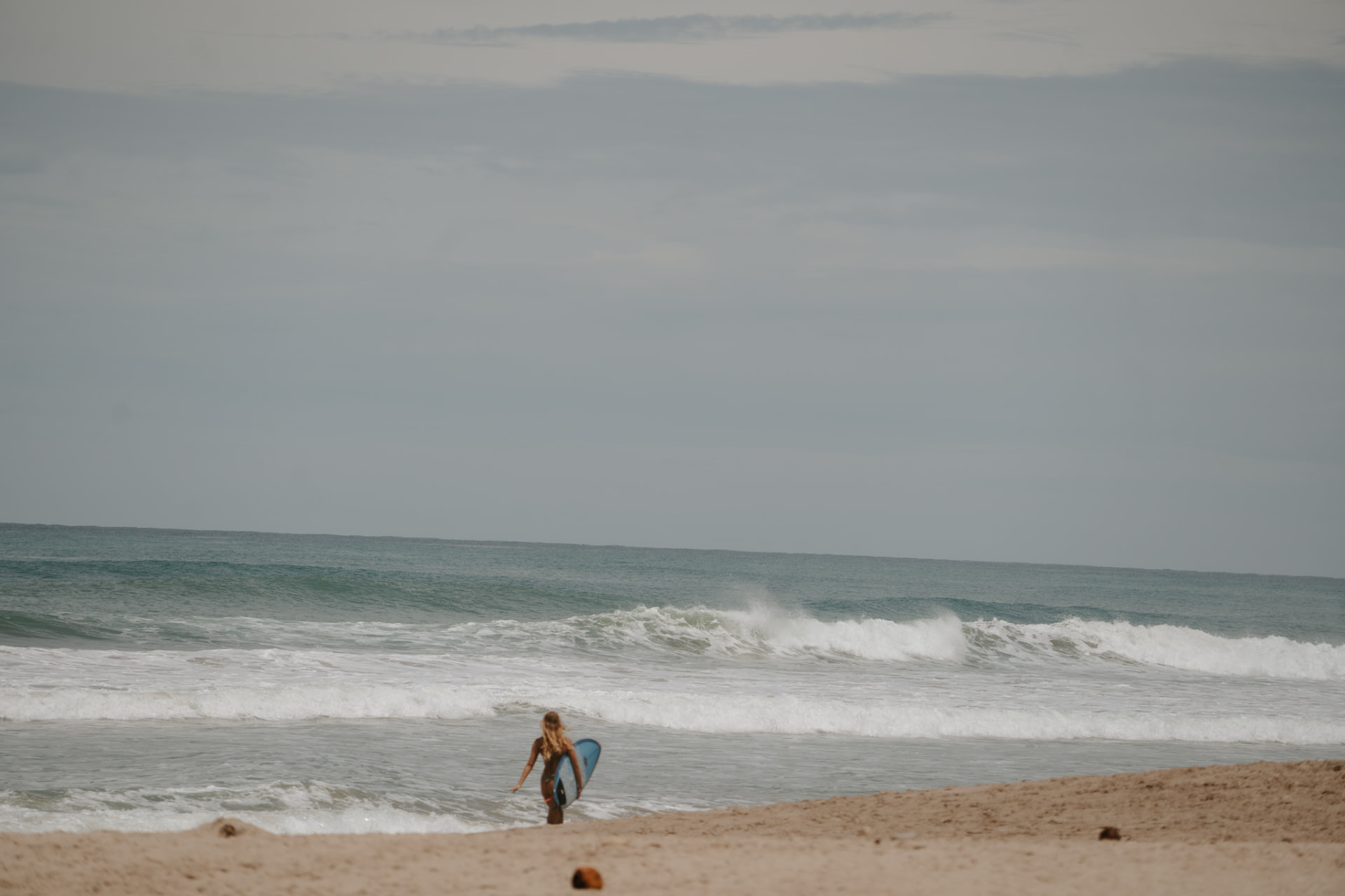 A lone surfer walking into the shorebreak in Santa Teresa, Costa Rica